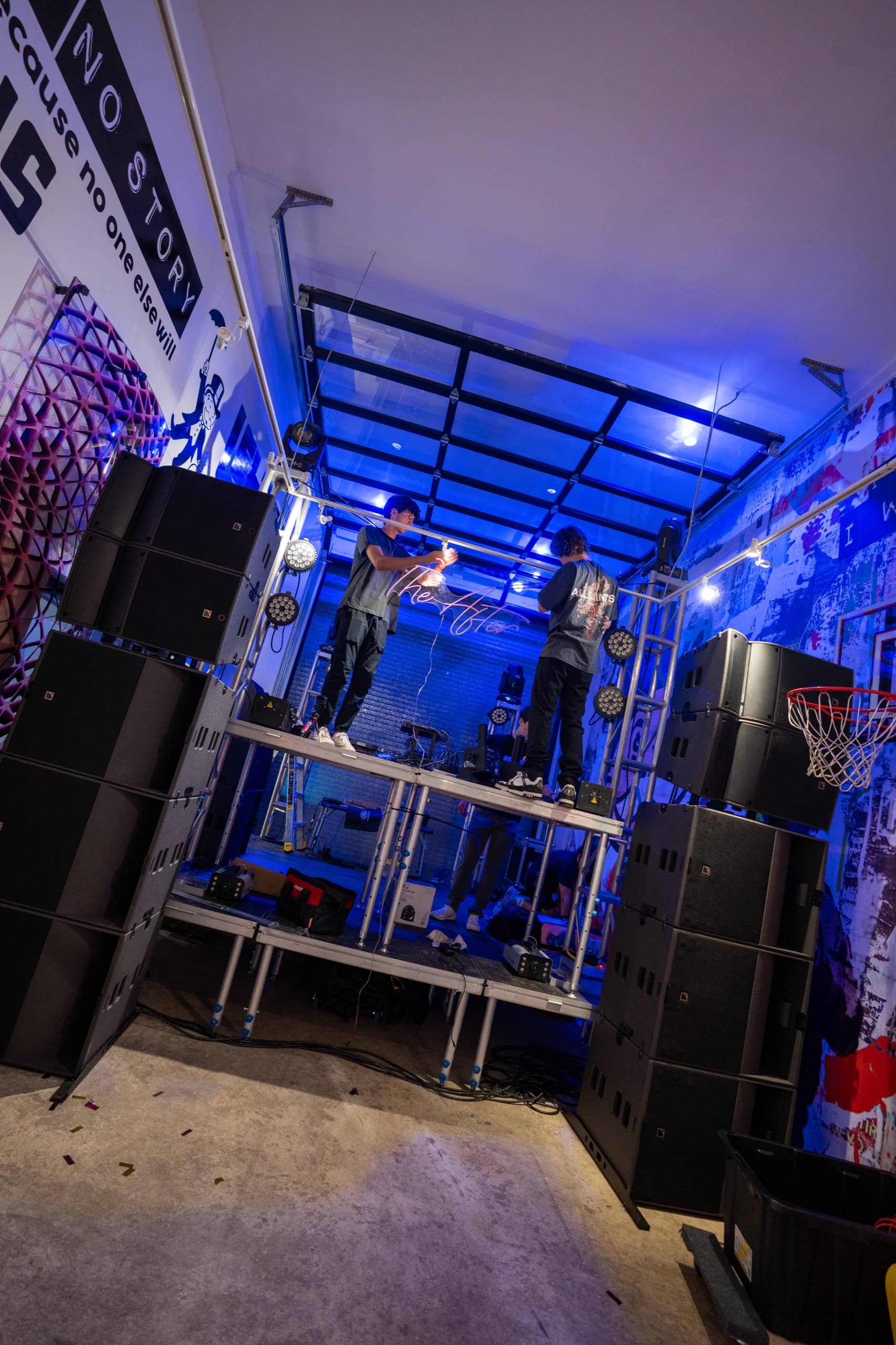 Nova crew assembling the stage and speaker stacks under blue work light before doors