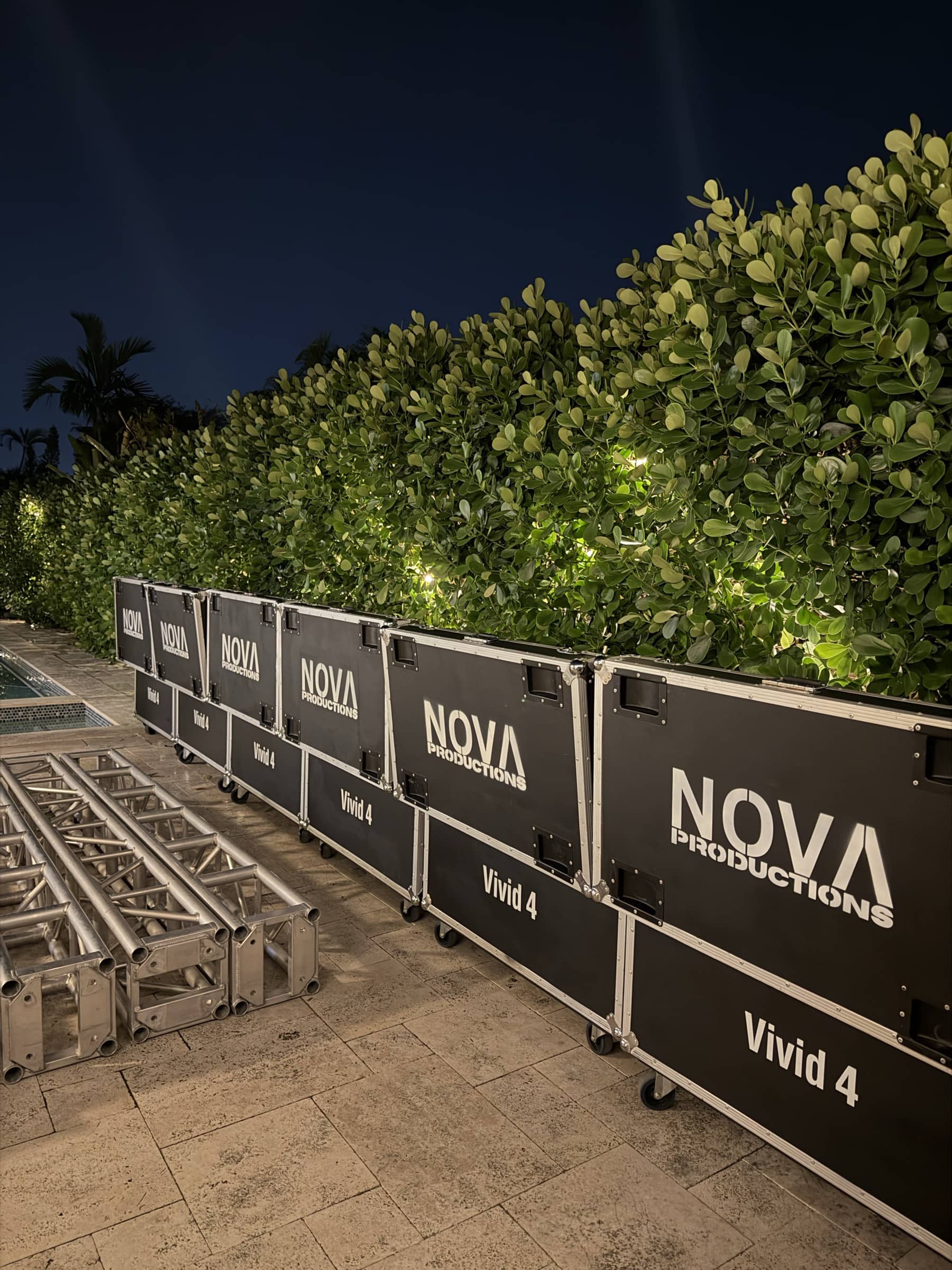 Nova LED panel road cases staged along a hedge after dark