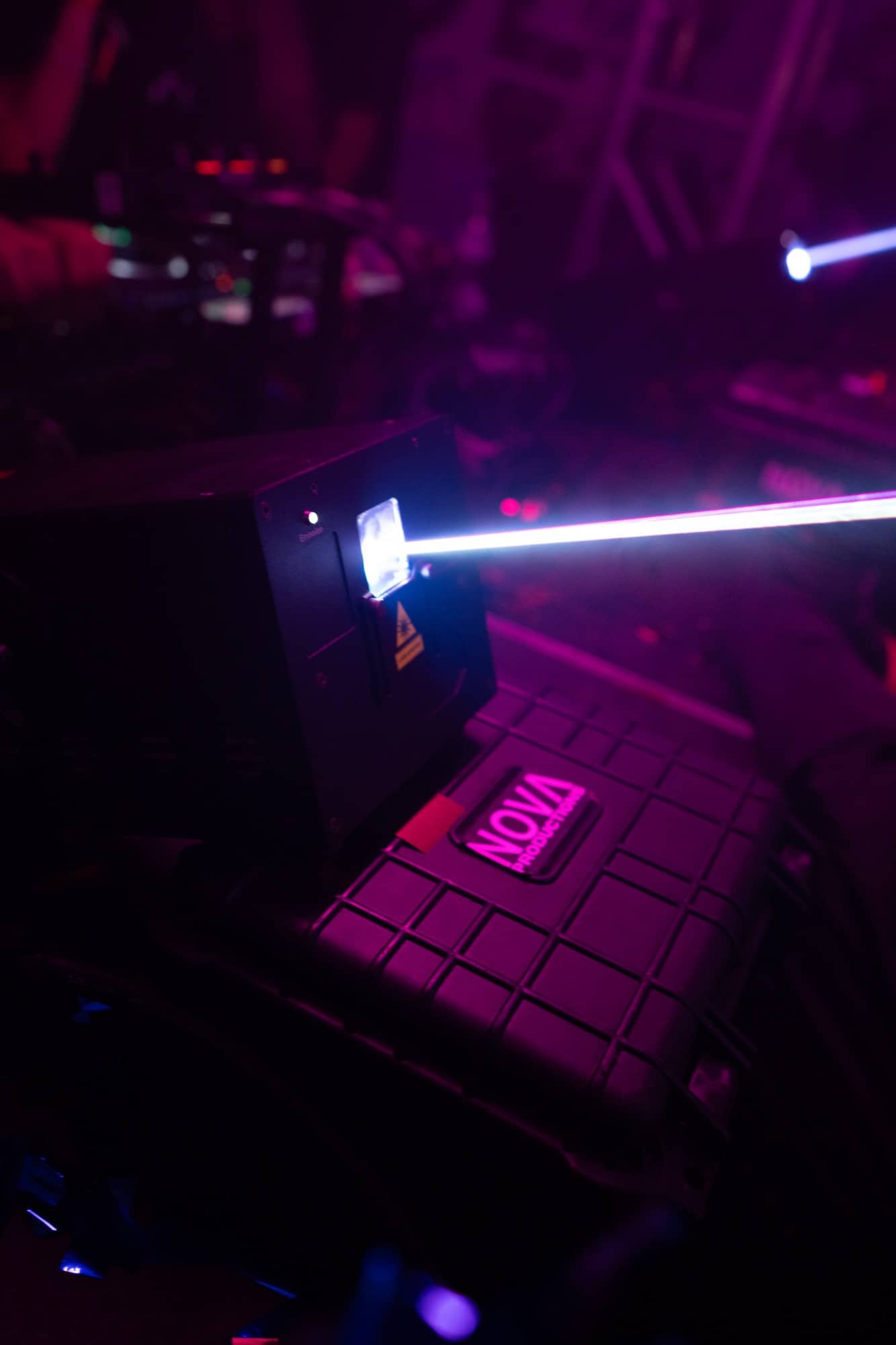 A show laser firing across a Nova Productions road case backstage