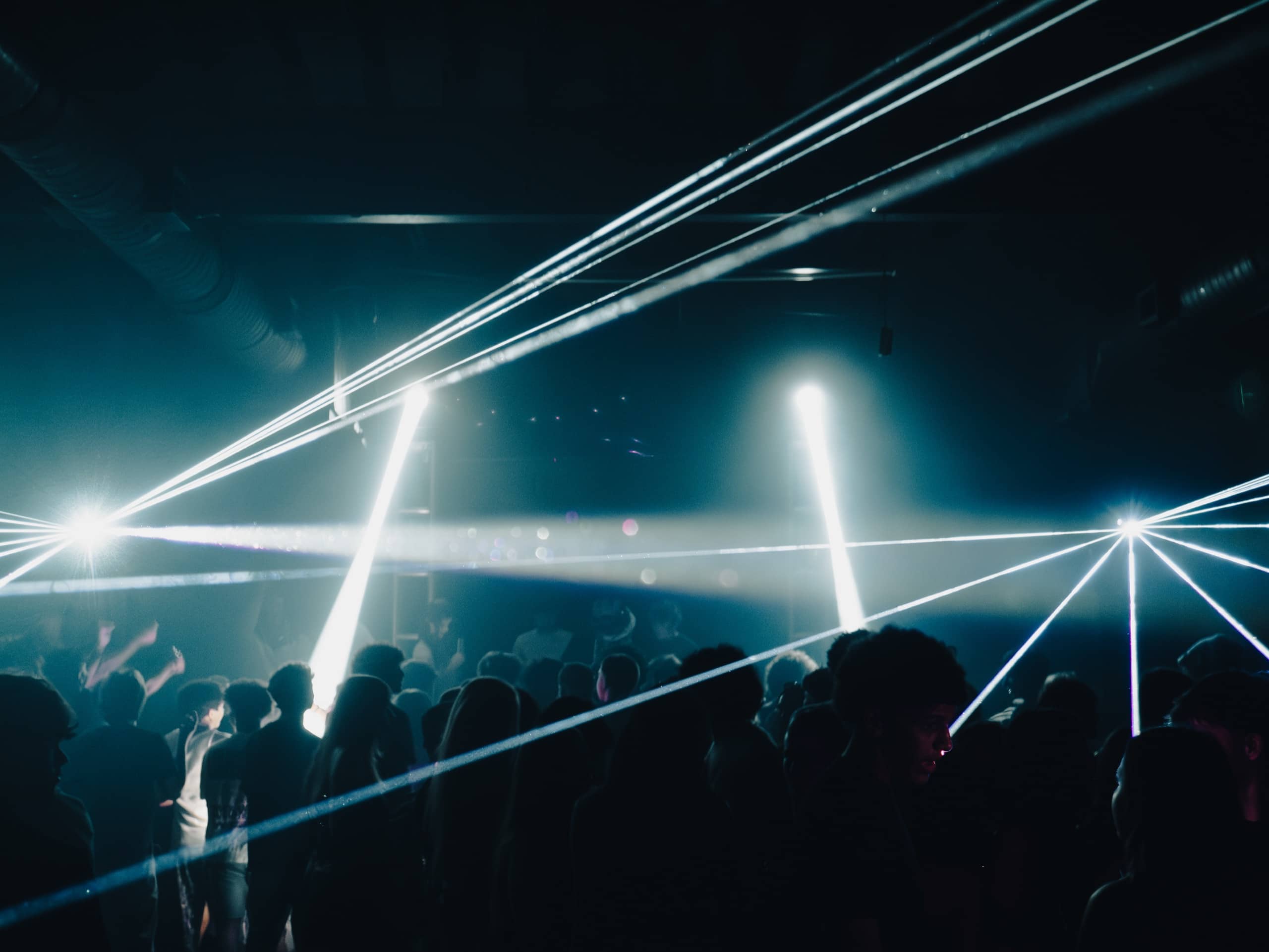 White laser beams crossing over a club crowd